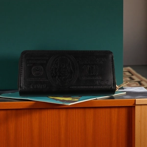 Macro shot of long black leather wallet with vintage 100 dollar bill pattern embossing