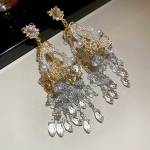 Close-up of golden vintage palace style earrings with crystal tassels and pearls