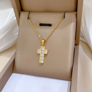 Detailed view of a gold titanium steel cross necklace with inset zircon on a jewelry box