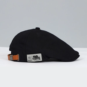 Detail of black canvas ivy cap featuring brown leather strap and silver metal buckle
