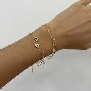 Close-up of dual-layer 18k gold-plated bracelets featuring heart and round crystal charms