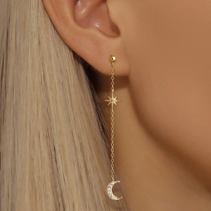 Detail of gold star and crescent moon tassel earrings with crystals on female model