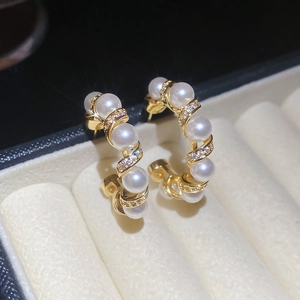 Close-up of gold-plated hoop earrings with pearls and zircon in a jewelry box