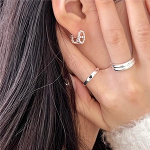 Detail of silver chain link earrings and heart ring paired with a cozy white sweater