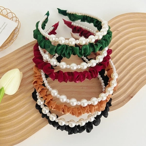 Close-up of colorful satin headbands with white pearl accents on a wooden tray
