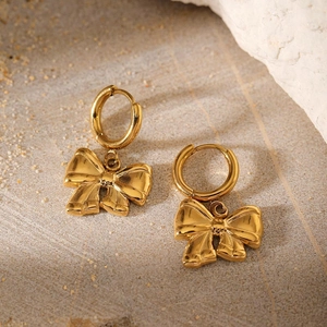 Macro view of gold-plated stainless steel bow earrings with polished finish and round hooks