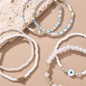 Handmade evil eye beaded bracelet set with white beads and gold heart charm on stone