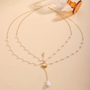 Detail of gold pearl body chain with seashell pendant and baroque pearl drop accent