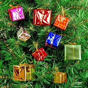 Gros plan de mini boîtes cadeaux colorées suspendues aux branches du sapin de Noël