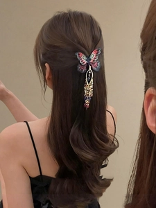 Détail d'une pince à cheveux papillon brodée avec pampilles perlées sur cheveux longs