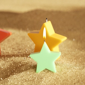 Set di candele a forma di stella con fiamma accesa su sfondo di sabbia dorata di lusso