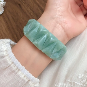 Detailed view of light green iridescent acrylic triangular beads on an elastic bracelet