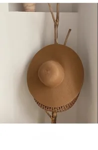 Détail d'un chapeau de paille à larges bords suspendu sur un support en bois épuré
