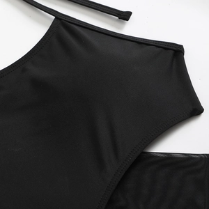 Detail of black long sleeve two-piece swimsuit with mesh stitching and strappy cutout design