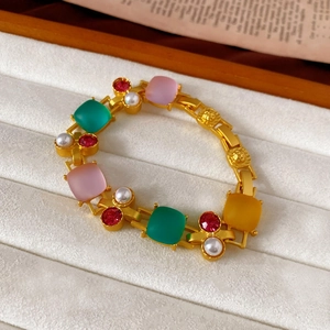 Detailed macro view of a vintage gold bracelet with colorful gems and pearl accents