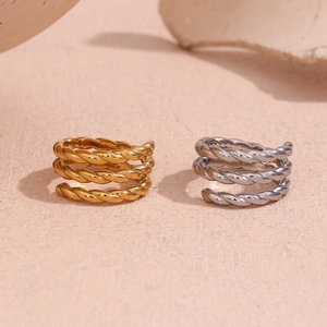 Detail of twisted rope spiral open rings in gold and silver finish on neutral background
