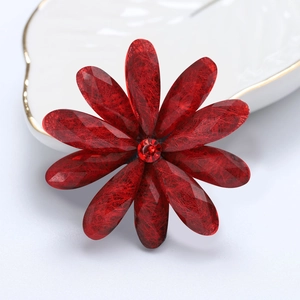 Macro detail of red acrylic flower brooch with resin petals and central rhinestone