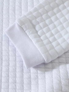 Detailed close-up of white quilted sweatshirt sleeve with ribbed cuff texture