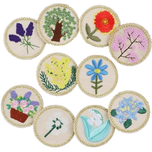 Macro detail of round floral embroidery patches with gold wire edges and vibrant silk threads