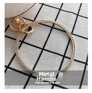 Close-up of golden circular handle with rows of sparkling rhinestones and swivel clasp