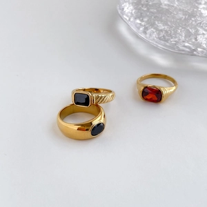 Close-up of golden rings with black stones and red ruby in a minimalist setting