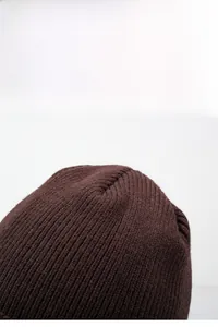 Detailed texture of dark brown knit beanie with ribbed wool blend pattern for winter