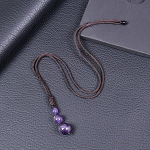 Natural amethyst beaded pendant necklace on dark brown braided cord with leather background