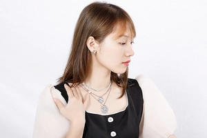 Detail view of layered silver-toned necklaces and matching relief stud earrings on model