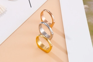 Close-up of three brushed metal signet rings in gold, silver, and rose gold finishes