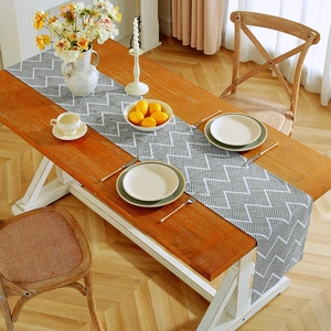 Detail of grey and white herringbone table runner on a wooden surface in a dining room