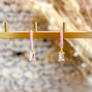 Detail view of pink enamel gold earrings with rectangular crystal drops on a display stand