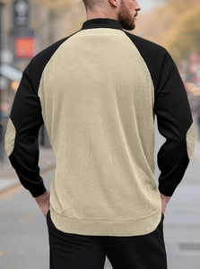 Detail of men's color-block knit sweater showing khaki torso, black sleeves, and elbow patches