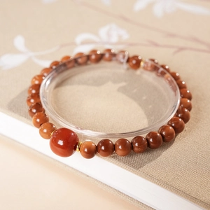 Macro shot of red agate beads bracelet with gold spacers on a decorative book