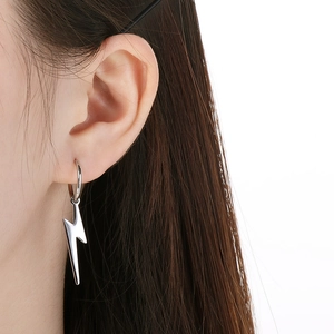Detailed view of polished silver lightning bolt earring worn on a model ear