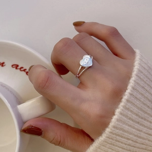 Detailed view of silver heart-shaped smiley face ring with dual band on model's hand