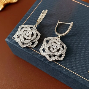 Close-up of silver hollow flower earrings with micro-set zircons on a jewelry box