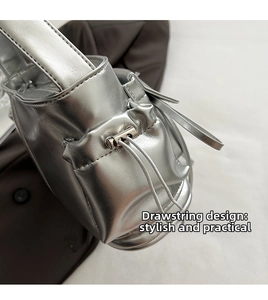 Detail of silver metallic baguette bag showing adjustable side drawstring and metal buckle