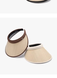 Detail of woven straw sun visors with elegant trim and metal logo button ornament