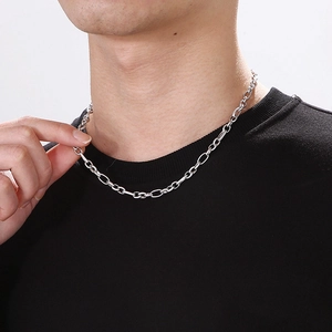 Detailed close-up of a silver titanium steel oval link chain necklace on a male model