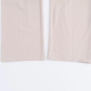 Close-up detail of the hem and fabric texture of apricot high-waist wide-leg trousers