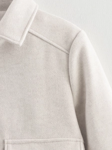 Detail aus weichem Tweed-Stoff mit sauberen Nähten an Revers und Tasche der Damenjacke