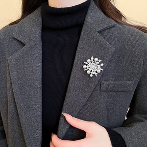Detail of silver snowflake brooch with white pearls and sparkling zircons on a grey blazer