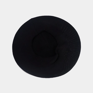 Détail de la texture d'un béret noir en maille avec motif en croissant et tissu doux