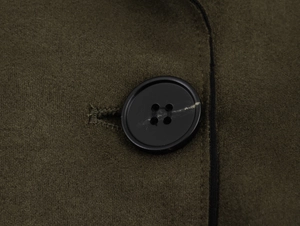 Détail d'un bouton noir à quatre trous sur le tissu vert olive à effet daim