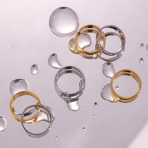 Artistic top view of gold and silver minimalist band rings on water drop surface