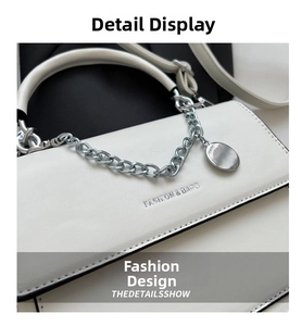 Close-up of white leather crossbody bag featuring silver chain and metal charm detail