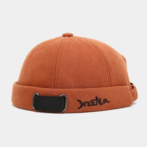 Detailed view of brown knit docker hat with black woven strap and letter embroidery