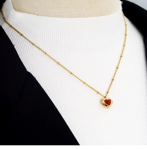 Detailed view of a gold-plated necklace with a 3D red heart pendant on a model