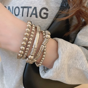 Gros plan de bracelets multicouches en métal argenté avec perles et détails texturés