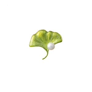 Detailed view of a green ginkgo leaf brooch featuring a single white pearl accent